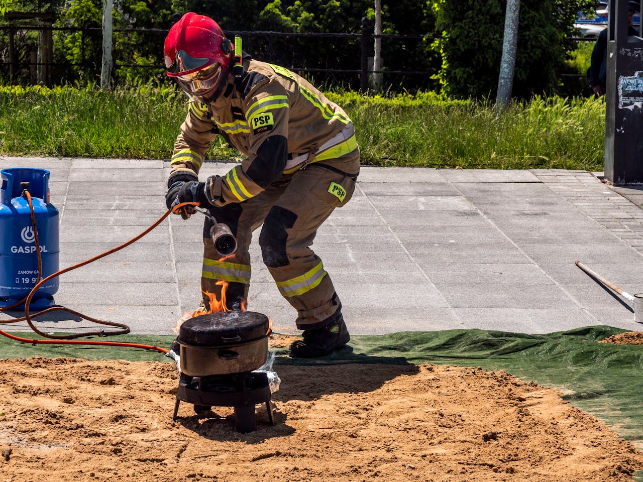 Services A firefighter safely ignites a controlled fire for a demonstration outdoors.